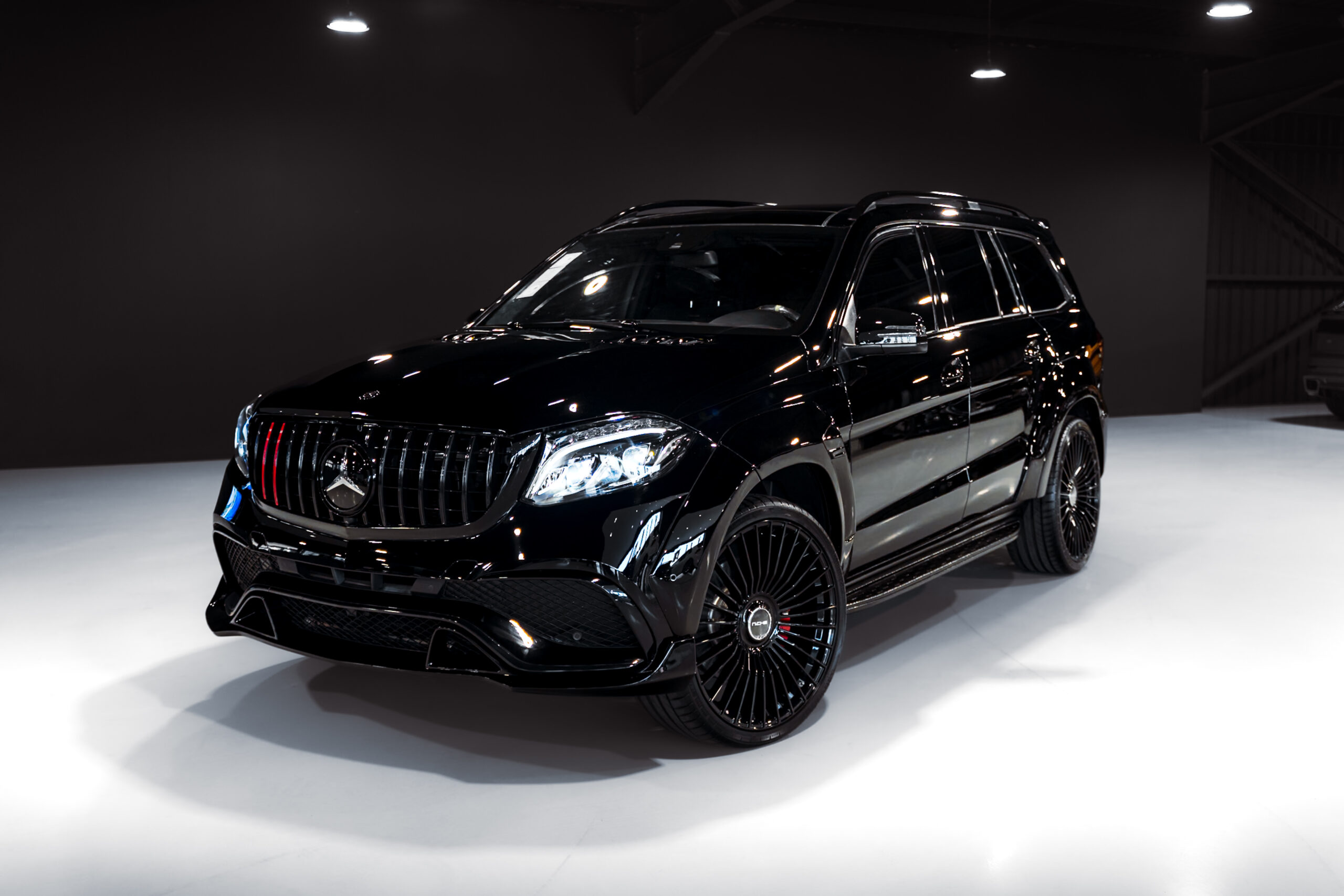 Black luxury SUV on display in a bright showroom, angled to show the front grille and wheel design.