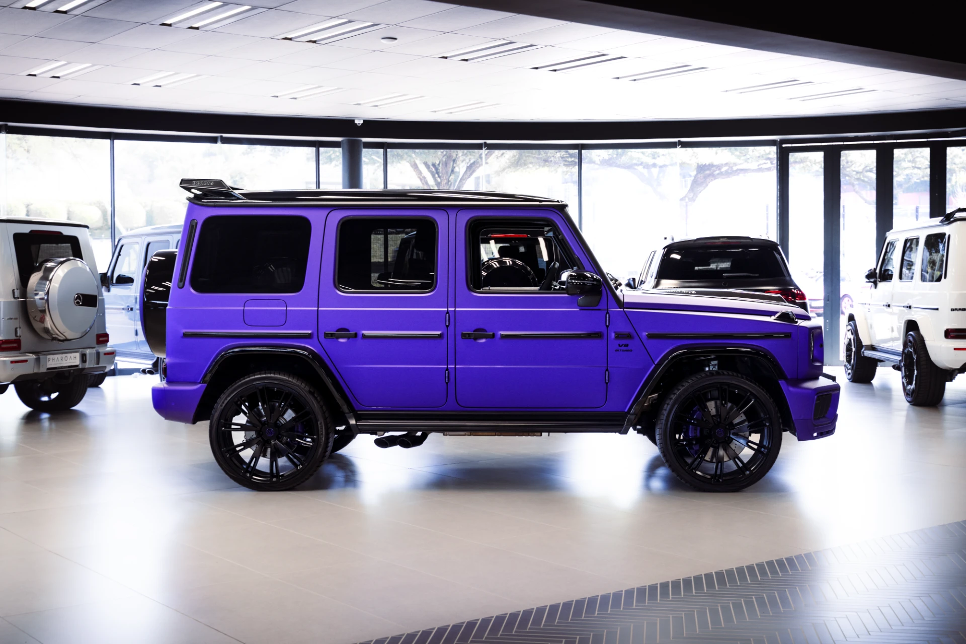 Purple luxury SUV on display in a car showroom with other vehicles and large windows in the background.
