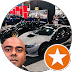 Selfie of a man outdoors with parked cars, overlaid by an orange badge with a white star.